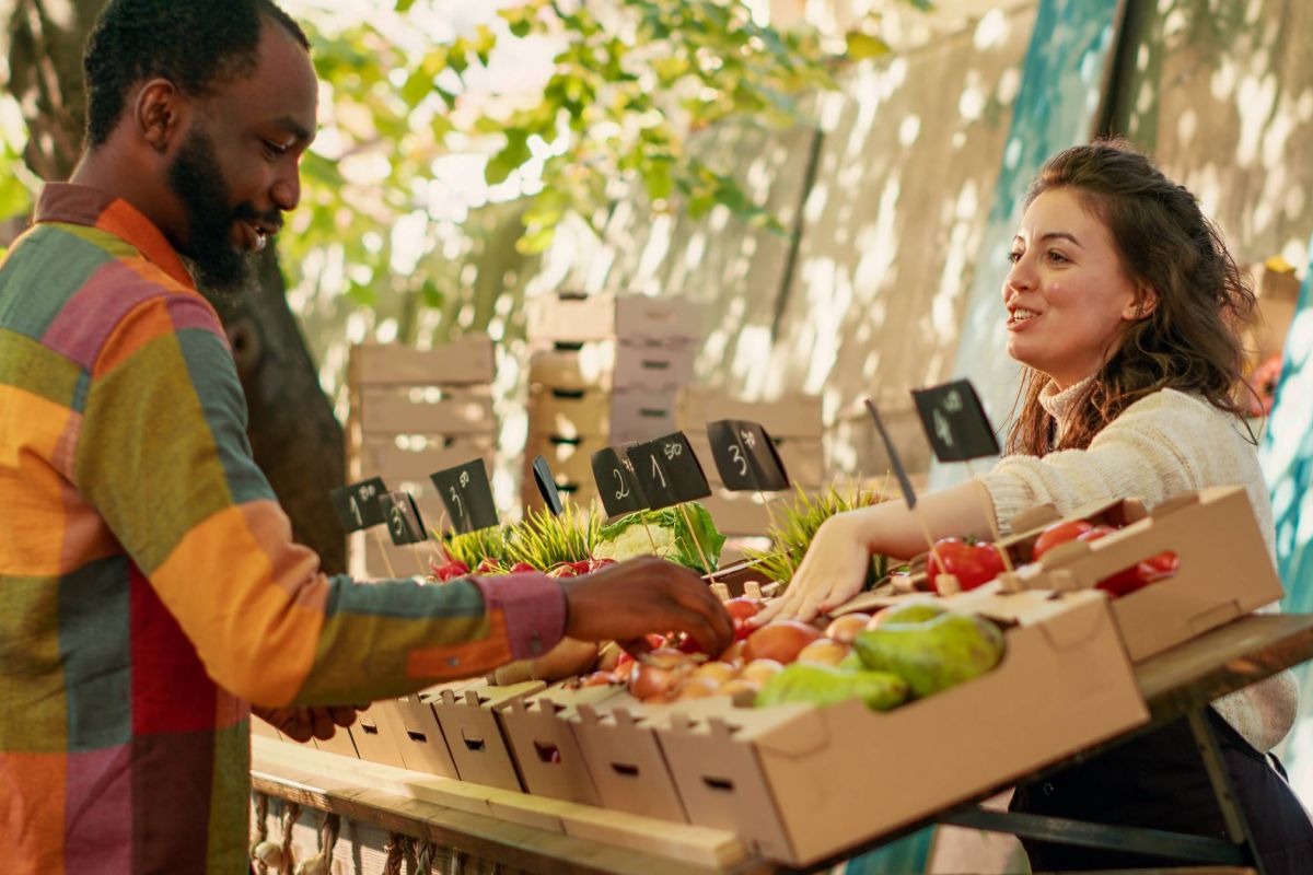 Woman at a farmer's market selling fruits and vegetables to a man