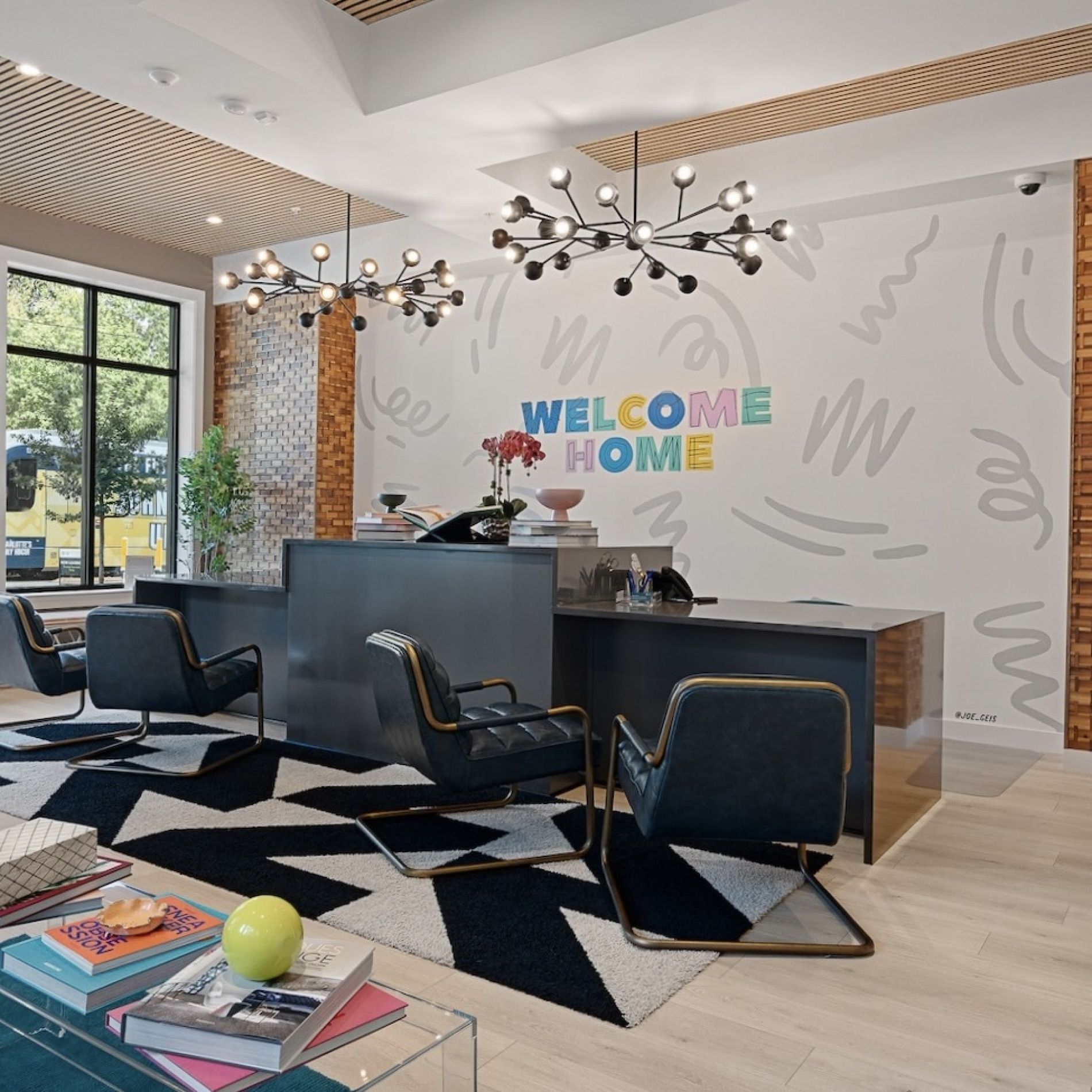 Reception area at Hawthorne 808 with stylish seating, a "Welcome Home" sign on the wall, and modern decor elements.